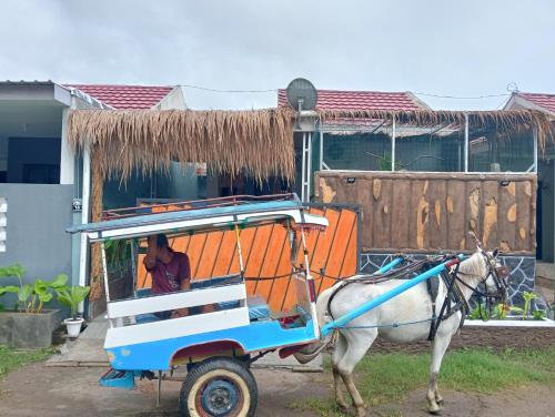 a horse pulling a cart with a person in it at BTN Mahkota Pemenang 13 Tamarin 3A in Pawenang