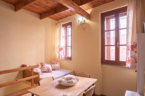 een woonkamer met een tafel, een bank en ramen bij La Cambusa Apartment in Alghero