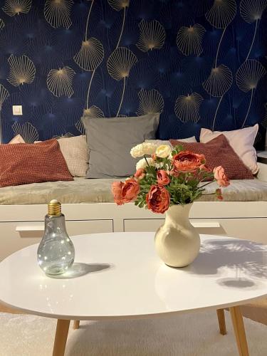 une table avec un vase de fleurs sur un lit dans l'établissement BEAU studio dans l hyper centre, à Strasbourg