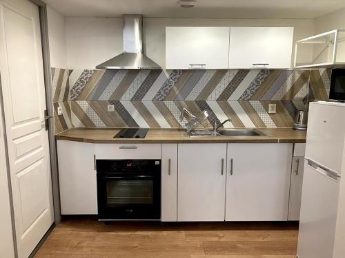 une cuisine avec des armoires blanches et un four noir dans l'établissement BEAU studio dans l hyper centre, à Strasbourg