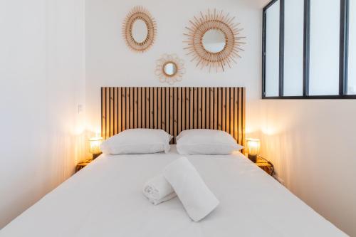 - une chambre avec un lit blanc et 2 miroirs sur le mur dans l'établissement Ile d'arz - studio - centre-ville, à Vannes