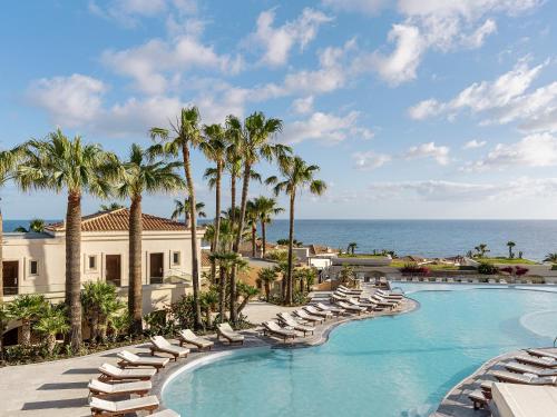 a swimming pool with lounge chairs and the ocean at Grecotel Marine Palace & Aqua Park in Panormos Rethymno