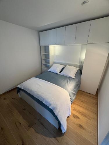 - une chambre avec un lit aux murs blancs et du parquet dans l'établissement Annecy centre et lac, à Annecy