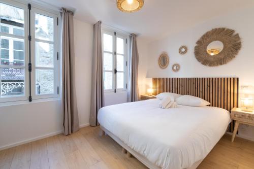 une chambre avec un grand lit blanc et des fenêtres dans l'établissement Île aux moines - T2 - centre ville - wifi, à Vannes
