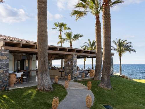 a house on the beach with palm trees at Grecotel Marine Palace & Aqua Park in Panormos Rethymno