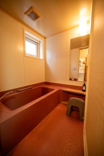 a bathroom with a tub and a sink and a mirror at 中町ハウス in Biei