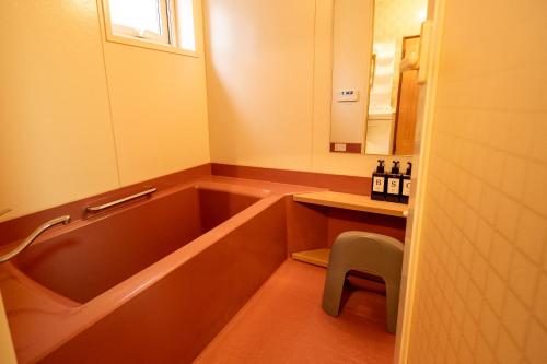 a bathroom with a tub and a stool and a mirror at 中町ハウス in Biei