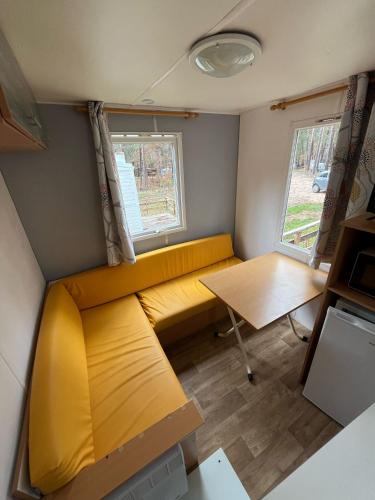 a small room with a yellow couch and a table at Camping Cobijo in Vinuesa