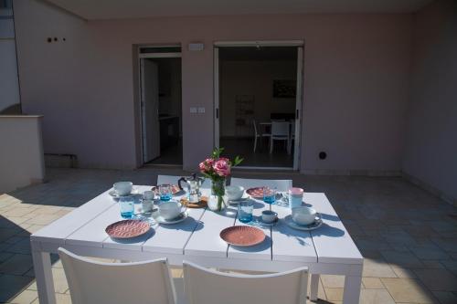 a white table with a vase of flowers on it at Le Casine di Cervia in Cervia