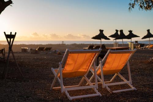 two beach chairs and umbrellas on a beach at La Mouette et les Dromadaires in Essaouira