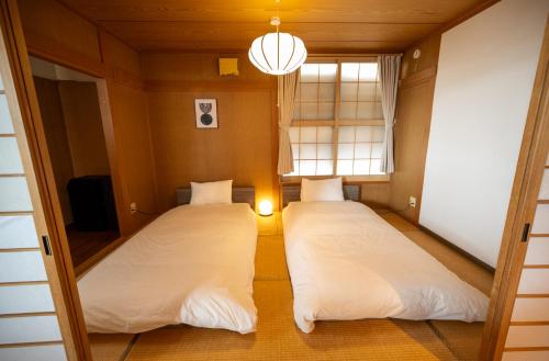 two beds in a small room with a window at 中町ハウス in Biei