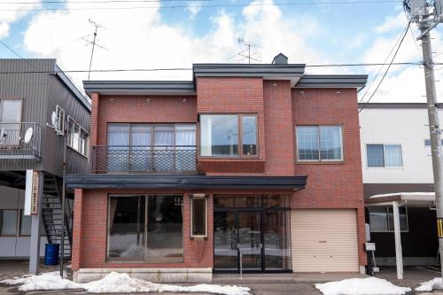 a red brick building with a garage at 中町ハウス in Biei