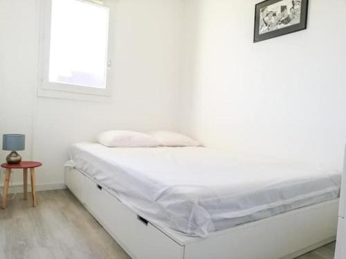 un lit blanc dans une chambre blanche avec une fenêtre dans l'établissement Superbe F2 avec balcon vue mer - 4 personnes, à Cabourg