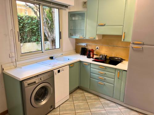 une cuisine avec des armoires vertes et une machine à laver dans l'établissement Magnificent apartment with garden on the beach, à Roquebrune-Cap-Martin