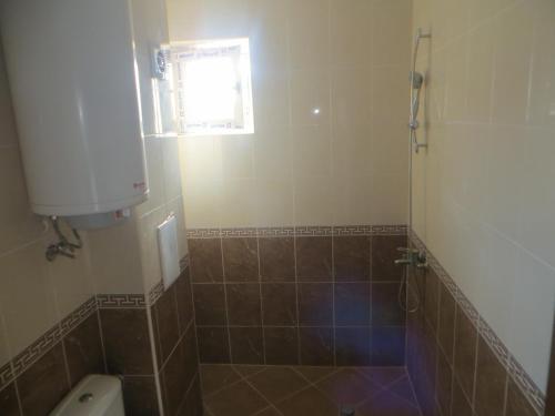 uma casa de banho com um chuveiro, um WC e uma janela. em Emona Apartment em Burgas