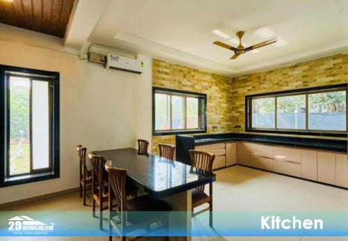 a dining room with a table and chairs and windows at Rooms At Harbour View Villa in Matralipāda