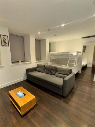 a living room with a couch and a bunk bed at Sleep 9 20 mins from London Waterloo BP172 in London