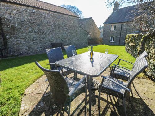 a table with chairs and a bottle of wine on it at South View in Leyburn