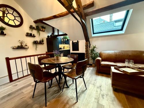 een woonkamer met een tafel, stoelen en een bank bij L'Evidence, appartement authentique - Epernay in Épernay
