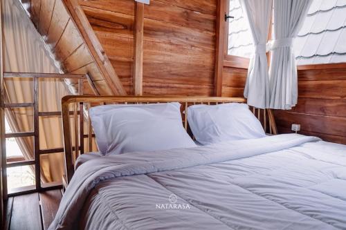 a bed in a room with a wooden wall at NATARASA Cottage in Ciwidey