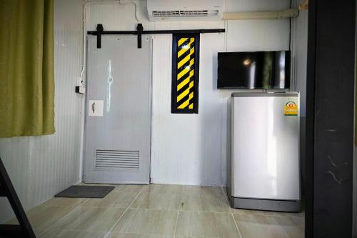 a room with a refrigerator and a door with a clock at Kua Car Camp in Lampang