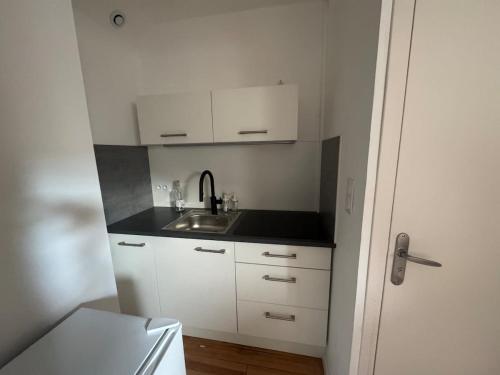eine kleine Küche mit einem Waschbecken und weißen Schränken in der Unterkunft Studio cosy gare de St-Pierre-Des-Corps in Saint-Pierre-des-Corps