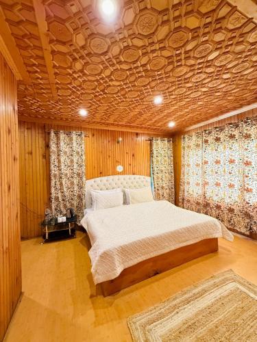 a bedroom with a large bed with a wooden ceiling at The Pinus Resort in Pahalgām