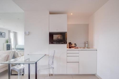 une cuisine avec des armoires blanches et une table en verre dans l'établissement Le Semiramis l Central & Views l Shellter Rentals, à Saint-Tropez