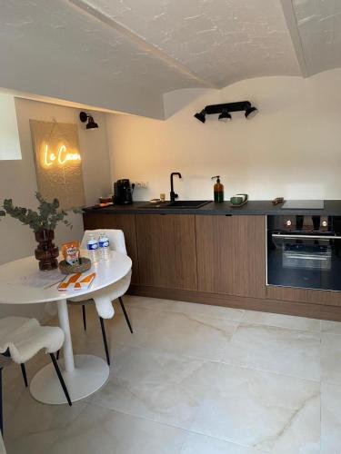 - une cuisine avec une table blanche et un comptoir dans l'établissement Le Cocon - proche gare avec jardinet - 2 adultes et 1 bébé, à Bois-le-Roi