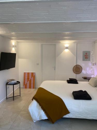 une chambre avec un grand lit blanc et une télévision dans l'établissement Le Cocon - proche gare avec jardinet - 2 adultes et 1 bébé, à Bois-le-Roi