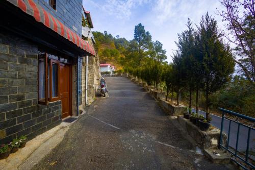 an empty street next to a building at Alaya Stays Kasauli Woods Cottage 3 BHK Retreat with Outdoor Lounge & Balcony in Patta