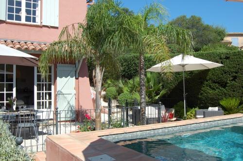 - une piscine avec un parasol et une maison dans l'établissement Villa Provençale 4 étoiles - Piscine & Jardin Zen, à Sainte-Maxime