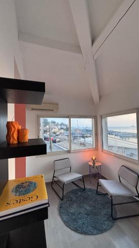 un salon avec des chaises, une table et des fenêtres dans l'établissement Appartement vu sur mer, à La Seyne-sur-Mer