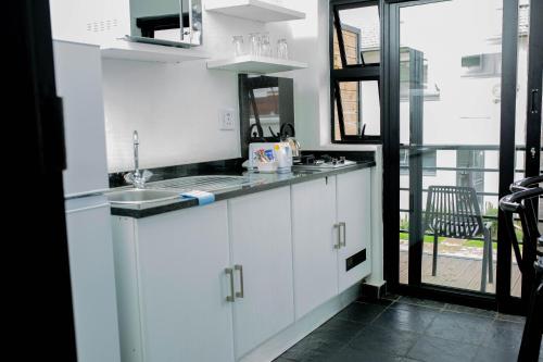a white kitchen with a sink and a window at Vetho 1 Apartments OR Tambo Airport in Johannesburg