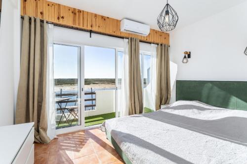 a bedroom with a bed and a balcony with a table at Cabanas de Tavira - T1 in Cabanas de Tavira