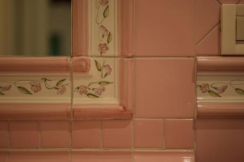 ein Badezimmer mit rosa Fliesen mit Blumen an der Wand in der Unterkunft Piazza Ariostea Apartment in Ferrara