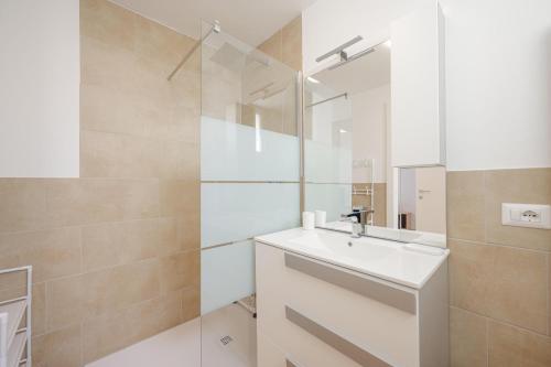 a white bathroom with a sink and a mirror at Wave Island A15 in Lido di Jesolo