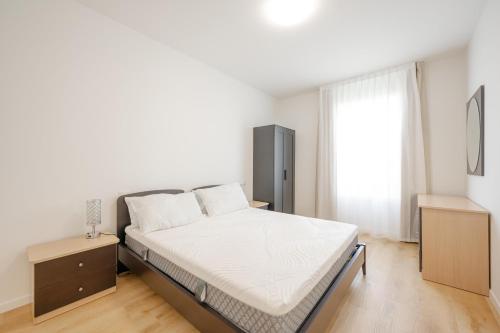 a white bedroom with a bed and a window at Wave Island A15 in Lido di Jesolo