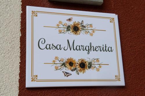 a picture of a sign on a wall with flowers at Welcomely - Casa Margherita in Varenna