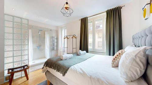 une chambre avec un grand lit blanc et des fenêtres dans l'établissement Le Leblois - Grande cuisine, à Strasbourg