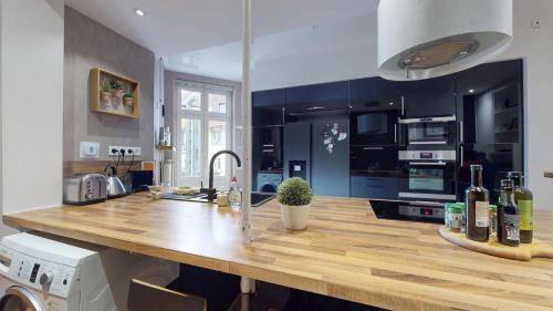 - une cuisine avec un comptoir en bois et des bouteilles de vin dans l'établissement Le Leblois - Grande cuisine, à Strasbourg