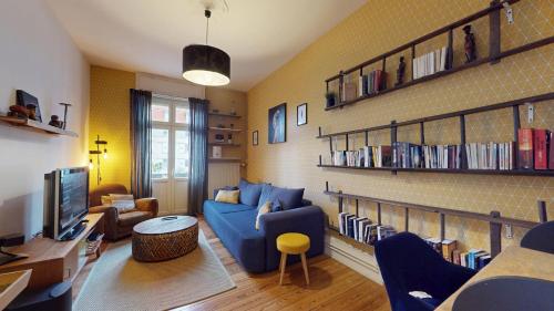 un salon avec un canapé bleu et une télévision dans l'établissement Le Leblois - Grande cuisine, à Strasbourg