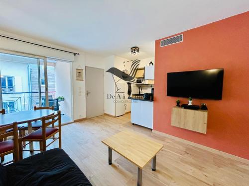 un salon avec une table et une télévision au mur dans l'établissement Le Repos du Marin - Au Port de Plaisance, à Rochefort