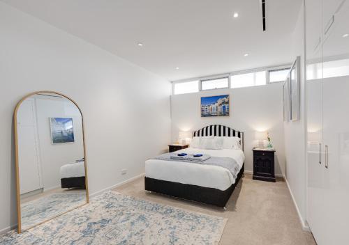 a bedroom with a large bed and a mirror at Henley Beachfront Luxury Home With Private Pool, Spa And Sauna! in Henley Beach