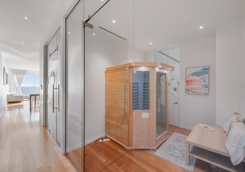 a room with a glass wall with a wooden cabinet at Henley Beachfront Luxury Home With Private Pool, Spa And Sauna! in Henley Beach