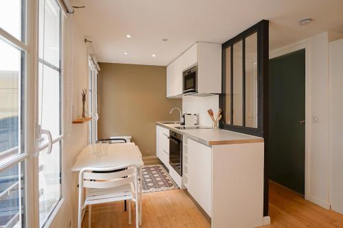 une cuisine avec un comptoir blanc et une table dans l'établissement Appartement chill au cœur du Marais, à Paris