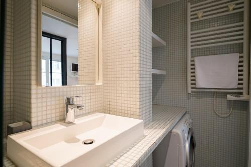 une salle de bain avec un lavabo et une machine à laver dans l'établissement Appartement chill au cœur du Marais, à Paris