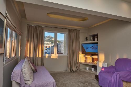 a living room with a purple couch and a tv at Lycabettus View Kaniggos in Athens