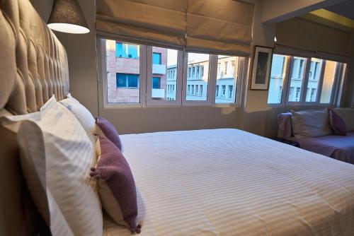 a bedroom with a large bed with white sheets and windows at Lycabettus View Kaniggos in Athens