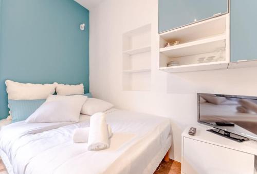 Cette petite chambre comprend un lit blanc et une télévision. dans l'établissement Le Portalet l Near the Port l Shellter Rentals, à Saint-Tropez